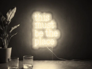 Neonskylt «This Must Be The Place» i varmvit LED-neon, monterad på vägg