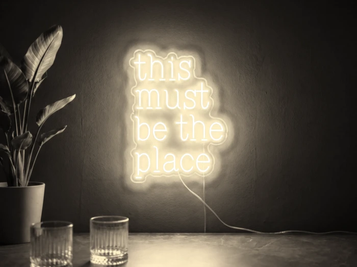 Neonskylt «This Must Be The Place» i varmvit LED-neon, monterad på vägg