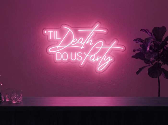 Neonskylt «Til Death Do Us Party» i rosa LED-neon, monterad på vägg