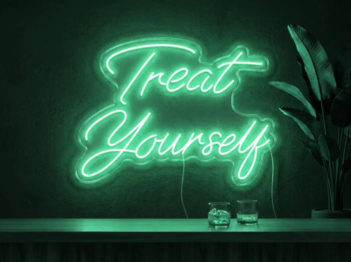 Neonskylt «Treat Yourself» i mintgrön LED-neon, monterad på vägg