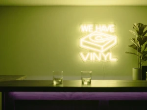 Neonskylt «We Have Vinyl» i gul LED-neon, monterad på vägg