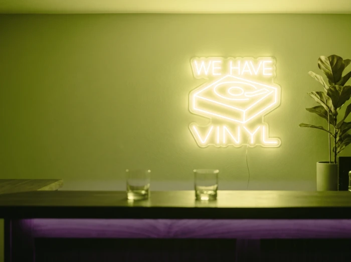 Neonskylt «We Have Vinyl» i gul LED-neon, monterad på vägg