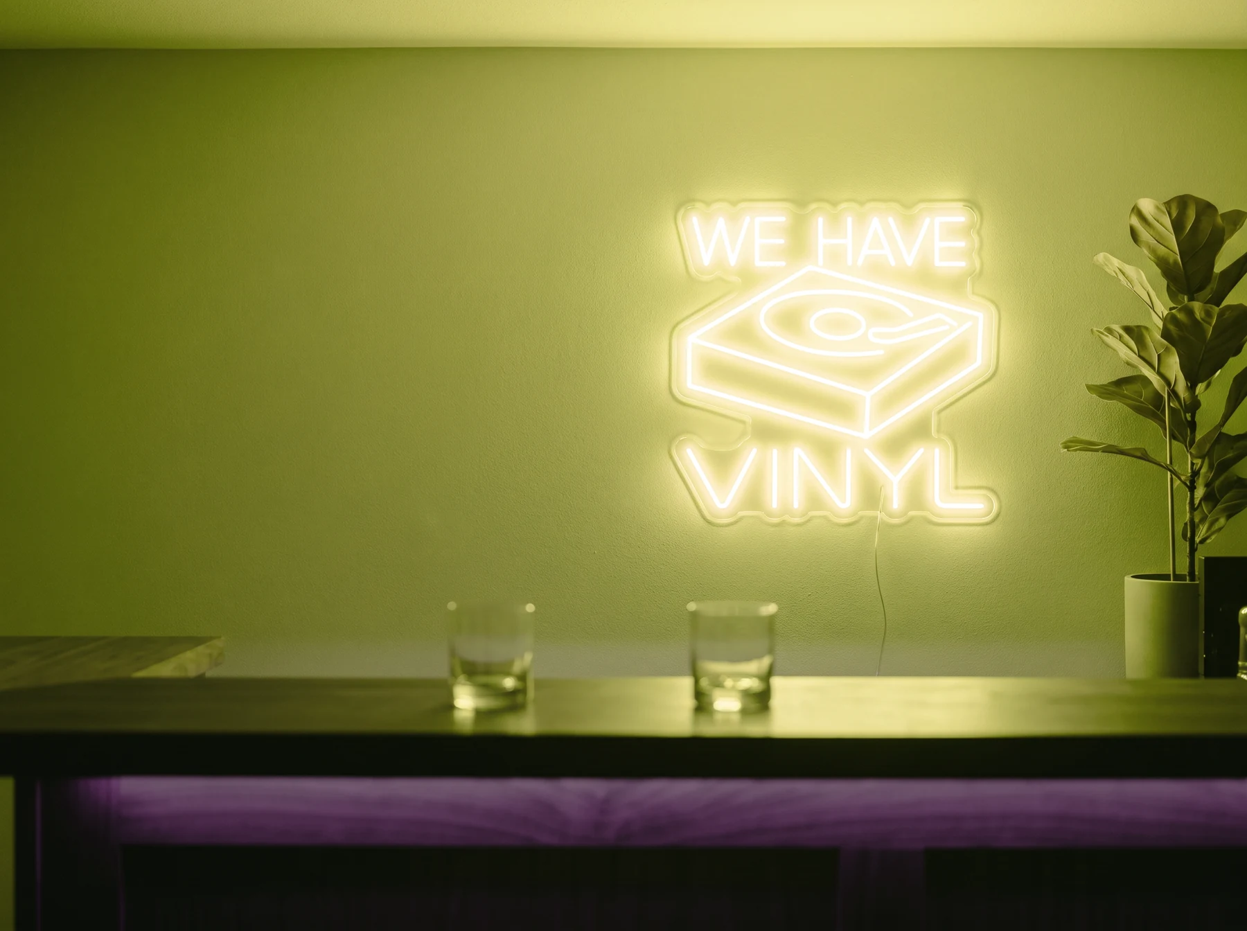 Neonskylt «We Have Vinyl» i gul LED-neon, monterad på vägg