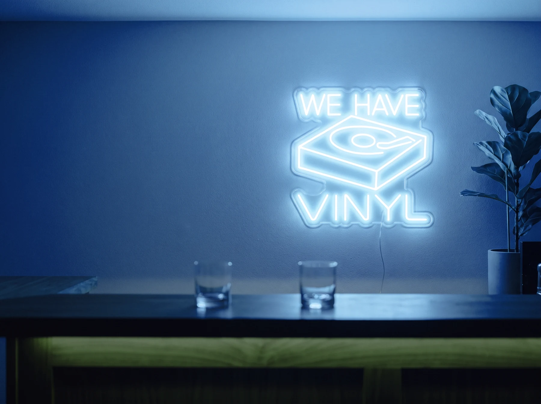 Neonskylt «We Have Vinyl» i isblå LED-neon, monterad på vägg