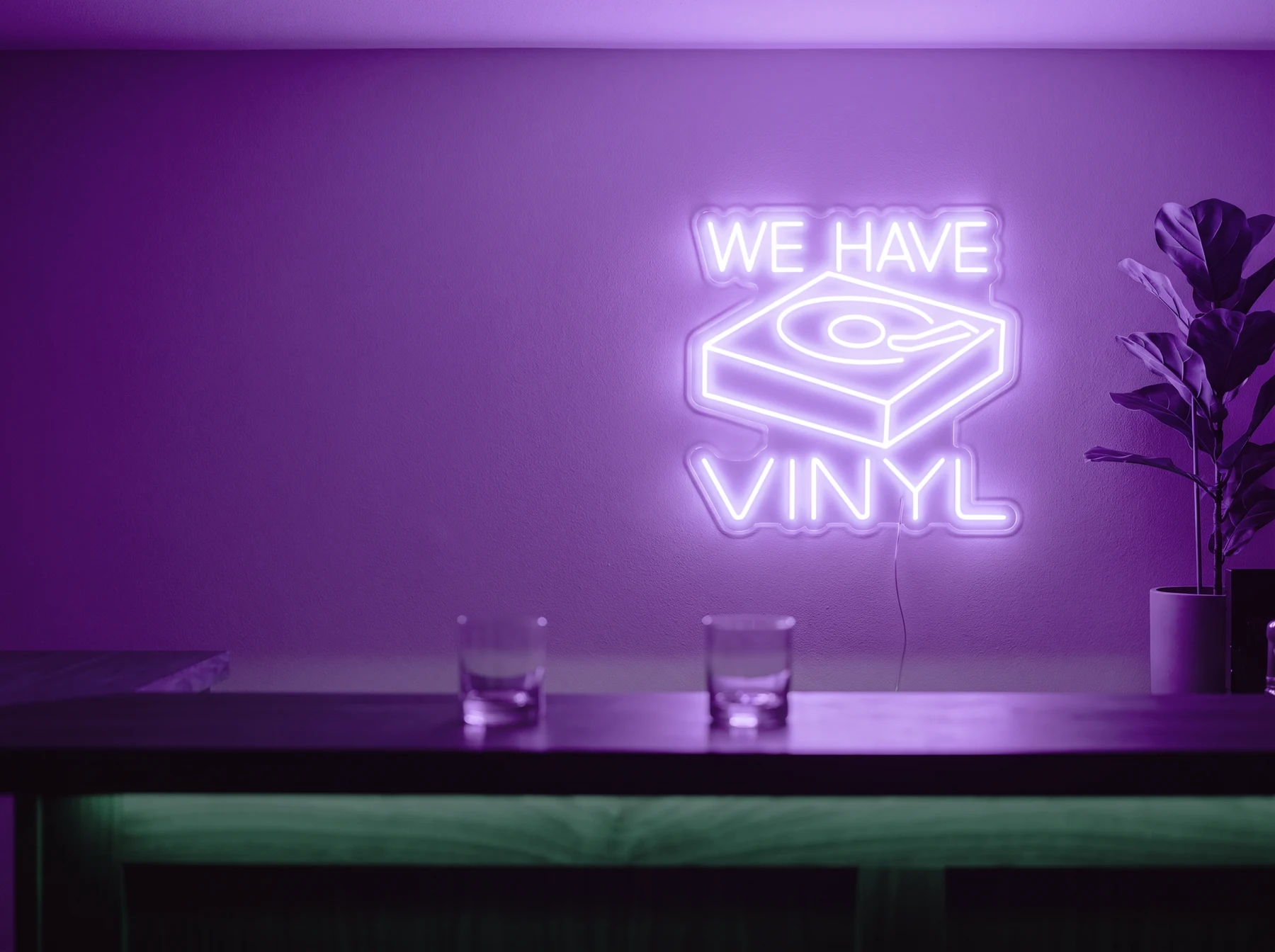 Neonskylt «We Have Vinyl» i lila LED-neon, monterad på vägg