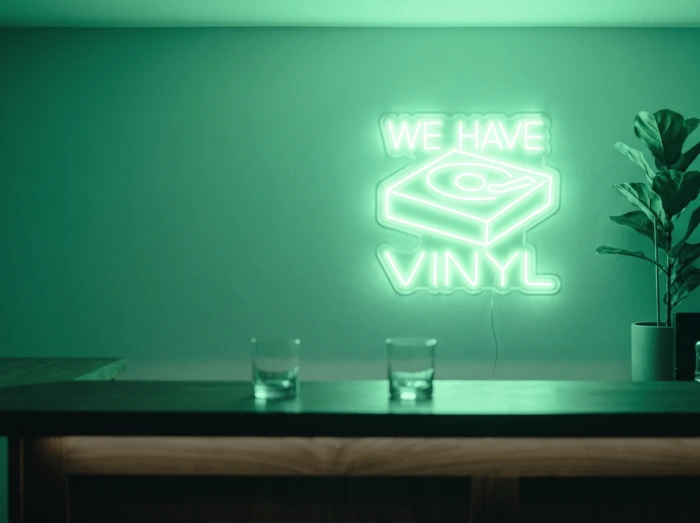 Neonskylt «We Have Vinyl» i mintgrön LED-neon, monterad på vägg