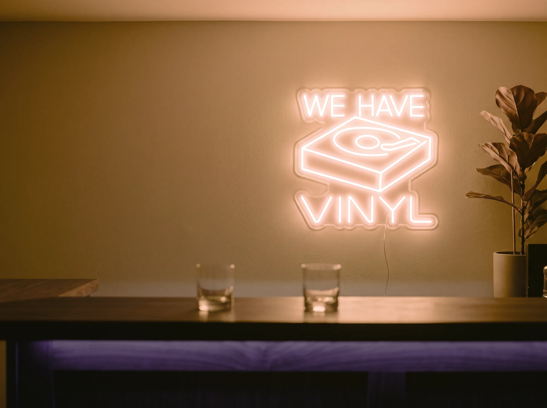 Neonskylt «We Have Vinyl» i orange LED-neon, monterad på vägg