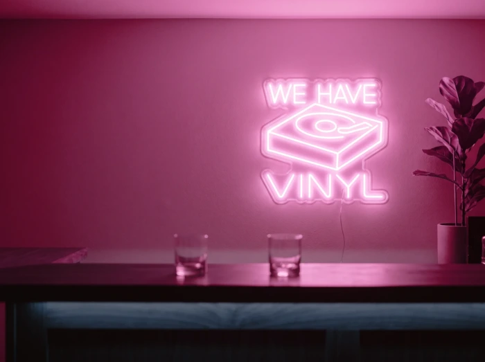 Neonskylt «We Have Vinyl» i rosa LED-neon, monterad på vägg