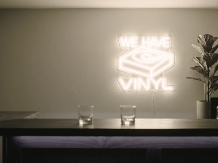 Neonskylt «We Have Vinyl» i varmvit LED-neon, monterad på vägg