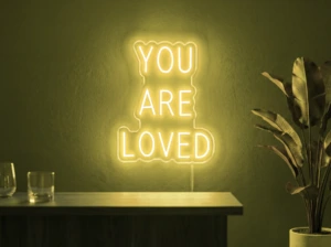 Neonskylt «You Are Loved» i gul LED-neon, monterad på vägg