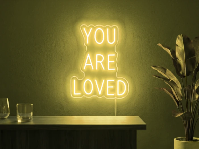 Neonskylt «You Are Loved» i gul LED-neon, monterad på vägg