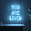 Neonskylt «You Are Loved» i isblå LED-neon, monterad på vägg