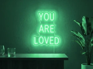 Neonskylt «You Are Loved» i mintgrön LED-neon, monterad på vägg