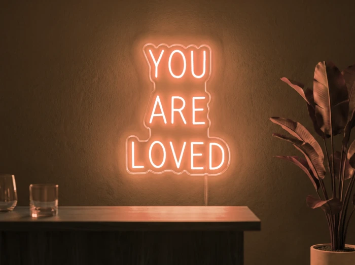 Neonskylt «You Are Loved» i orange LED-neon, monterad på vägg