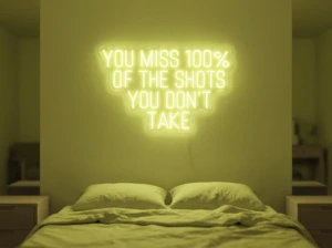 Neonskylt «You Miss 100% Of The Shots» i gul LED-neon, monterad på vägg