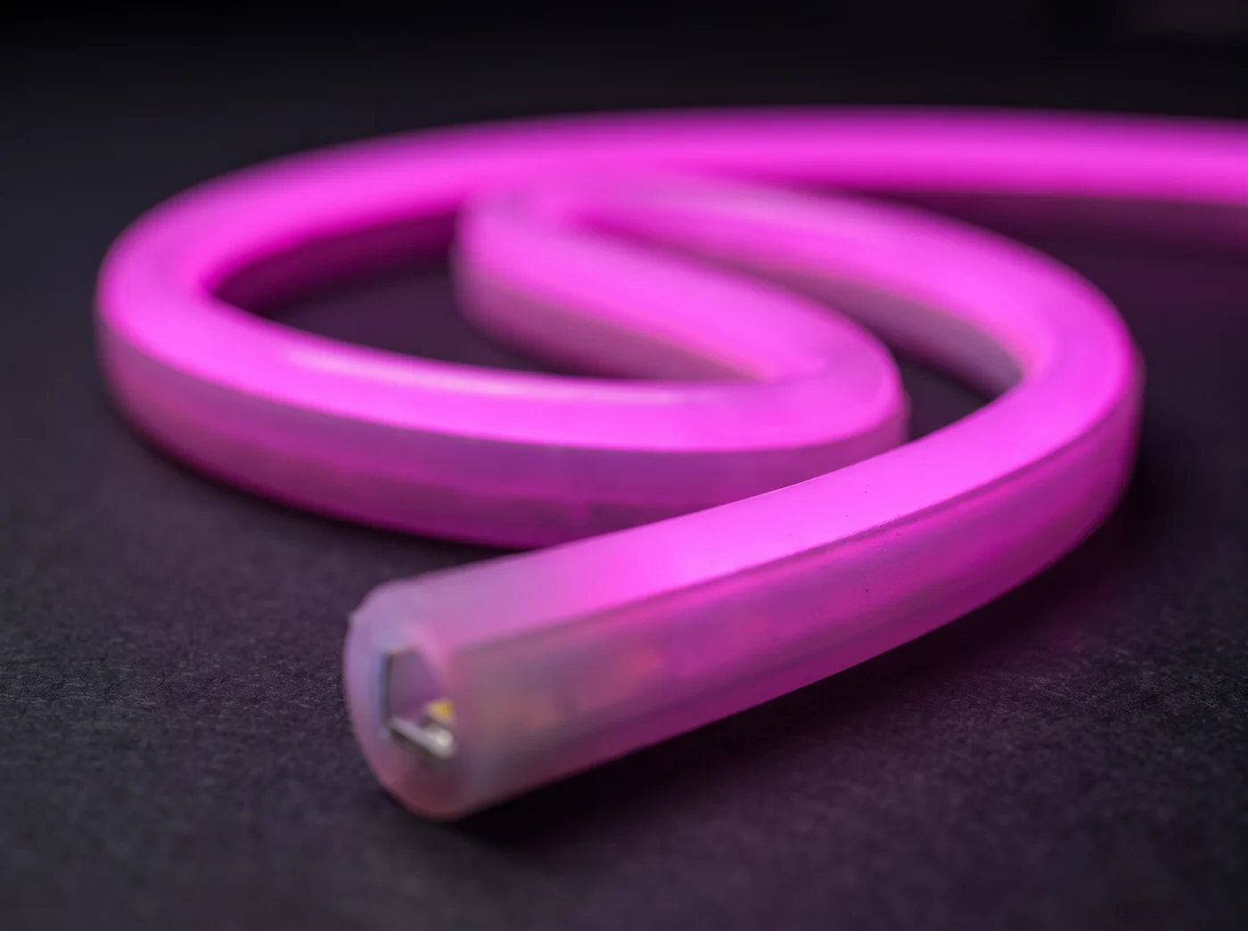 Närbild på flexibel silikonslang med LED-neon i rosa,
      avskuren så att lysdioderna inuti syns