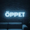Neonskylt «ÖPPET» i isblå LED-neon, monterad på vägg