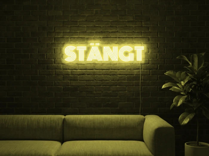 Neonskylt «STÄNGT» i gul LED-neon, monterad på vägg