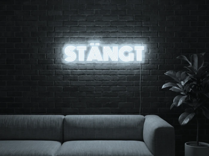 Neonskylt «STÄNGT» i iskall vit LED-neon, monterad på vägg