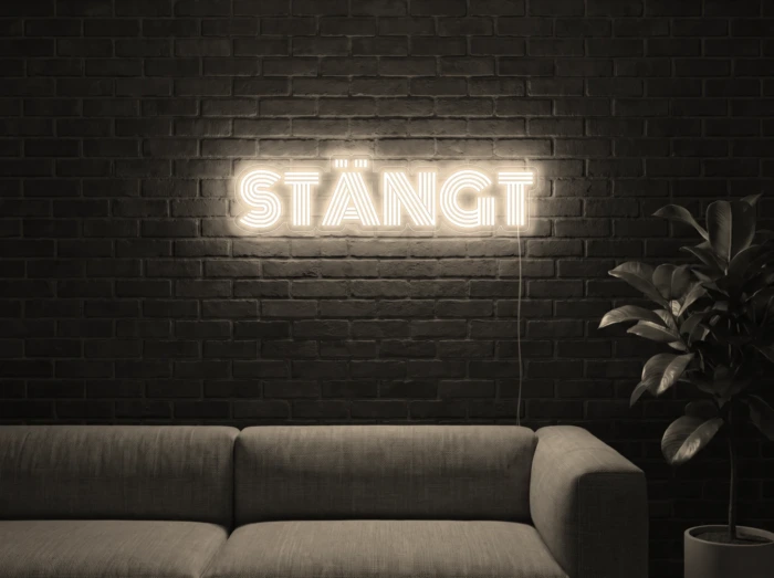 Neonskylt «STÄNGT» i varmvit LED-neon, monterad på vägg
